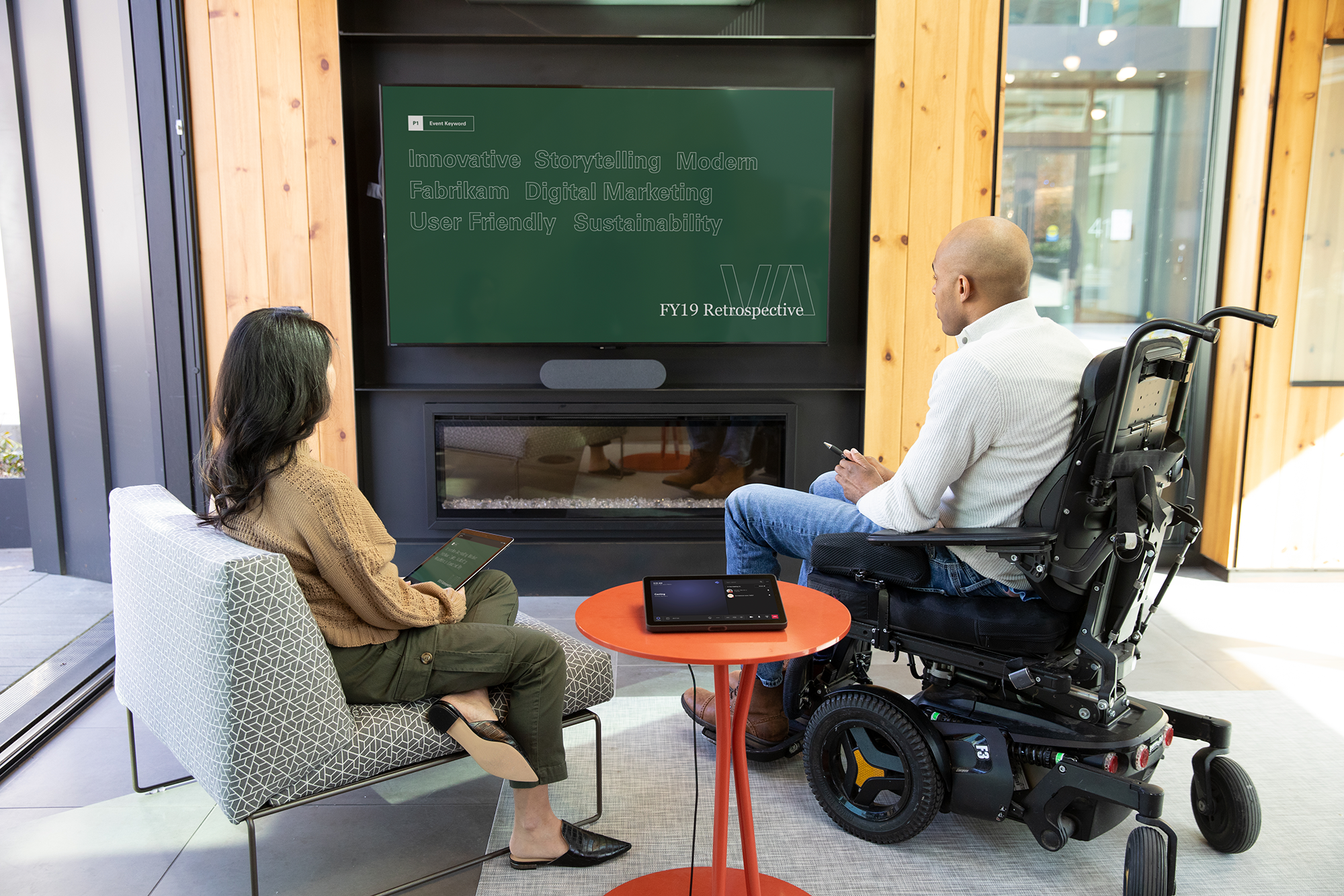 A photograph of a man in a wheelchair meeting with a woman standing.