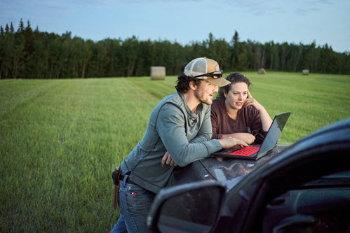 Photograph showing of farmers in a field looking at a tablet.