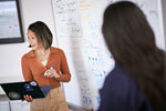 Photograph showing person working next to a whiteboard in an office.