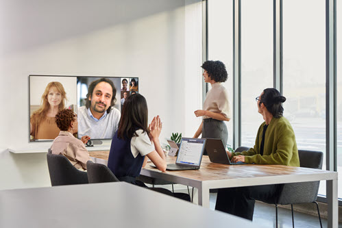 Photograph showing people in a virtual video meeting in a conference room.