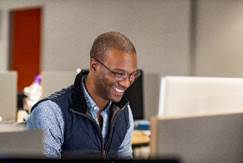 Foto di un uomo che sorride al monitor di un computer.